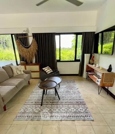 Charming living room with natural light, cozy seating, and lush garden view.