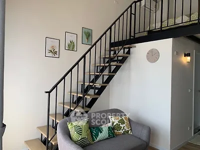 Modern loft apartment with stylish staircase and cozy living area, featuring decorative wall art and a comfortable sofa.