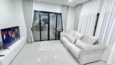 Modern living room with sleek design and large glass doors leading to dining area.