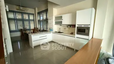 Modern kitchen with sleek white cabinetry and dining area in open layout