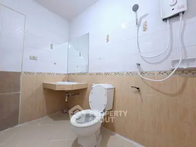 Spacious bathroom with modern fixtures and neutral tiles, featuring a shower and toilet.