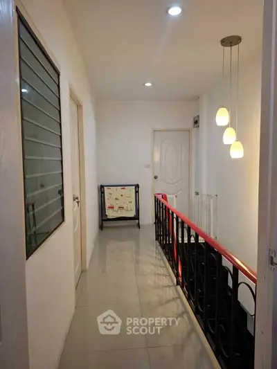 Bright hallway with modern lighting and sleek railing in a contemporary home.