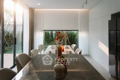 Elegant dining area with large windows and garden view, featuring modern decor and natural light.