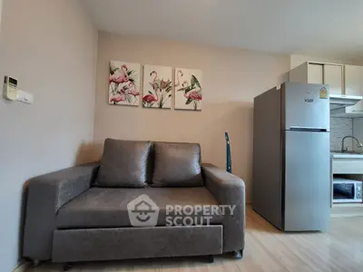 Cozy living room with modern sofa and kitchen area, featuring stylish flamingo artwork.
