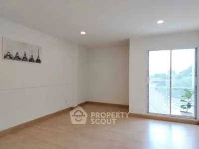 Spacious empty room with wooden flooring and large window view