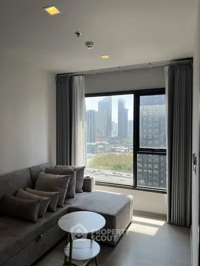 Modern living room with city view, featuring a cozy gray sofa and stylish decor.