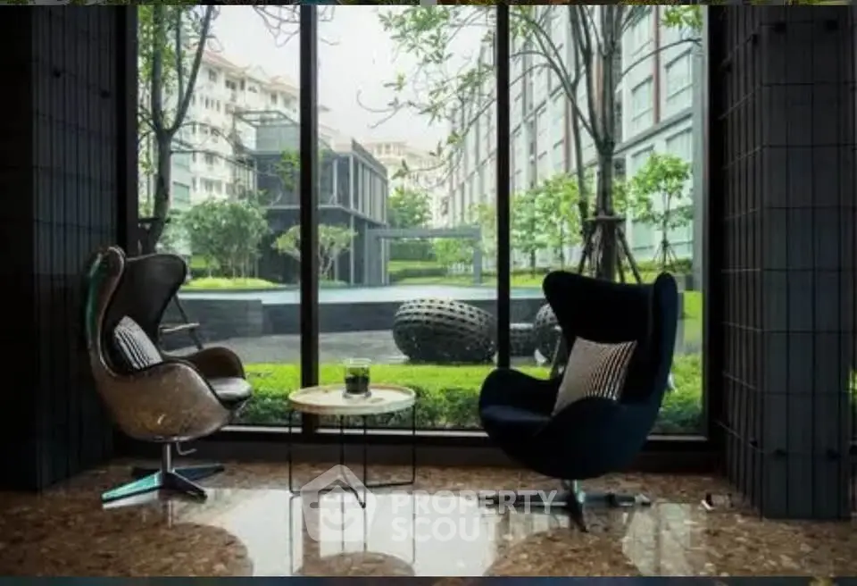 Luxurious modern living room with stunning garden view through large windows, featuring elegant chairs and marble flooring.
