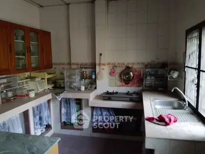 Cozy kitchen with gas stove and ample counter space, featuring wooden cabinets and a large window for natural light.