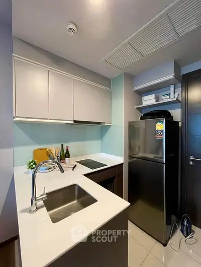 Modern compact kitchen with sleek cabinetry and stainless steel appliances in a stylish apartment.