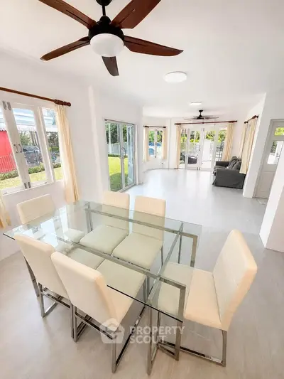 Spacious modern living and dining area with glass table and garden view