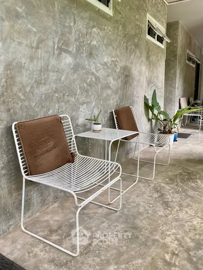 Chic outdoor patio with modern wire chairs and lush plants, perfect for relaxation and entertaining.