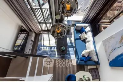 Modern loft-style living room with mezzanine and large windows offering city views.