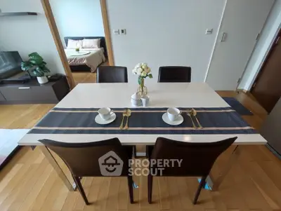 Modern dining area with elegant table setting in a stylish apartment, showcasing open layout and cozy bedroom view.