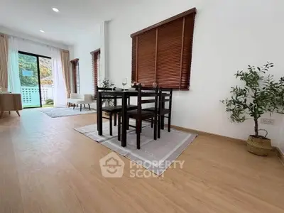 Spacious dining area with wooden flooring and large windows in modern apartment.
