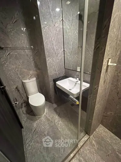 Modern bathroom with sleek marble tiles and glass shower enclosure.