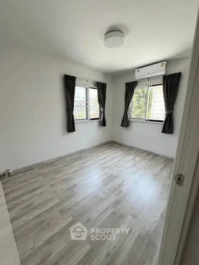 Spacious empty bedroom with large windows and modern flooring.