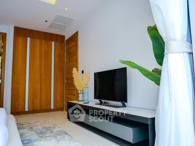 Modern living room with sleek TV stand and wooden accents, featuring a cozy ambiance and stylish decor.