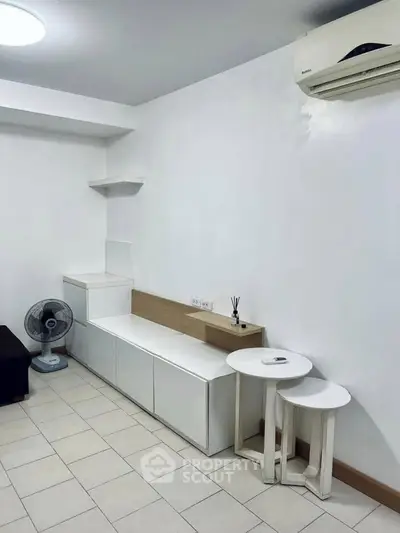 Modern minimalist living room with sleek white furniture and air conditioning unit.