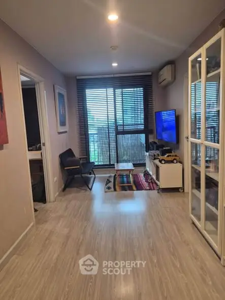 Modern living room with stylish decor and large window offering city view.