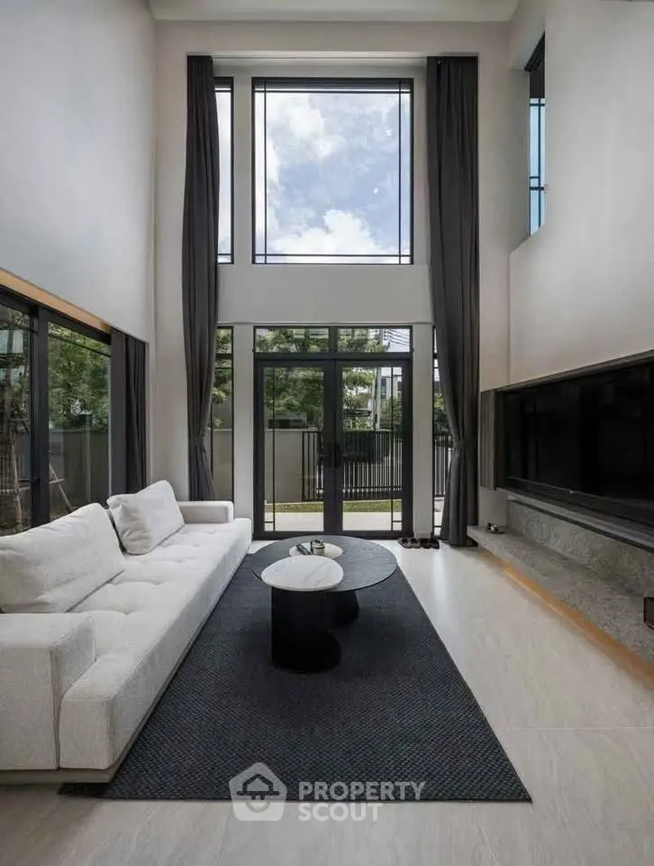 Luxurious high-ceiling living room with large windows and modern decor