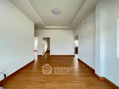 Spacious empty room with wooden flooring and white walls, ideal for customization.