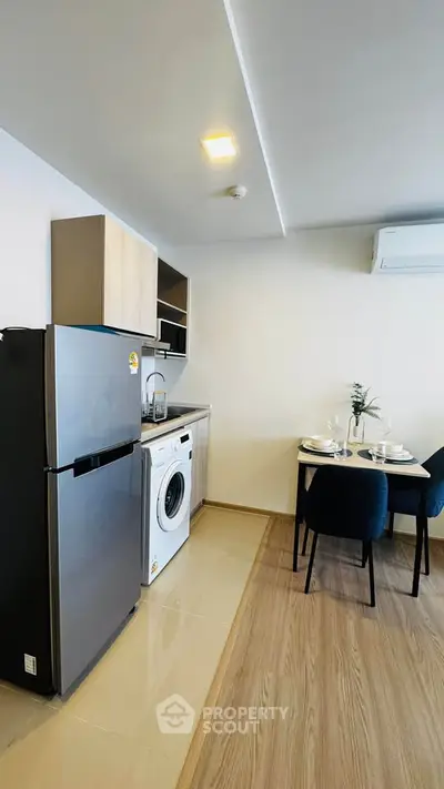 Modern kitchen with dining area, featuring fridge, washing machine, and elegant table setting.
