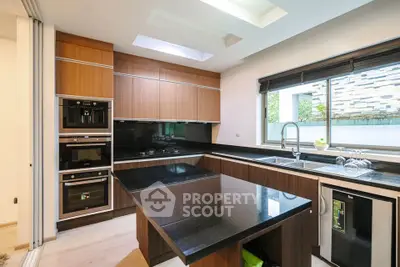 Modern kitchen with sleek black countertops and built-in appliances, featuring ample natural light and stylish cabinetry.