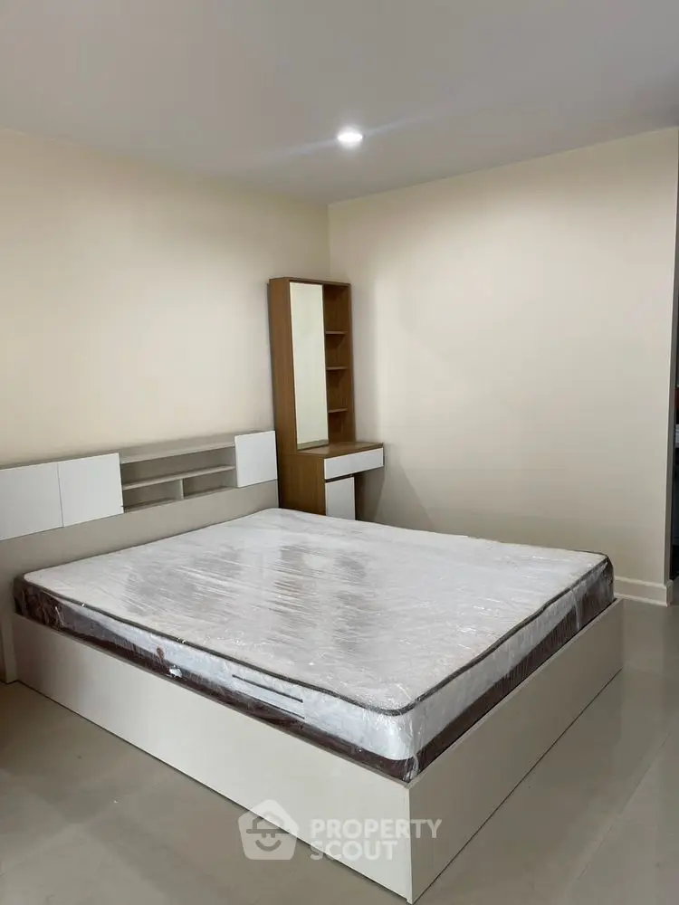 Modern bedroom with minimalist design featuring a bed and wooden furniture.