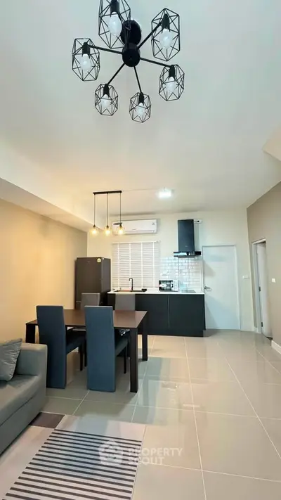 Modern open-plan living room and kitchen with stylish lighting and sleek furniture.
