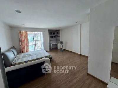 Spacious bedroom with wooden flooring and natural light, featuring a cozy bed and modern decor.
