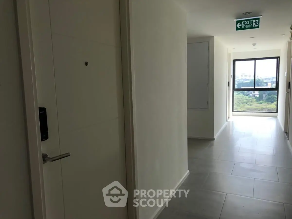 Modern apartment hallway with exit sign and window view