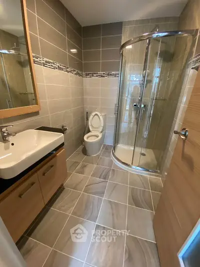 Modern bathroom with sleek shower and stylish sink in contemporary apartment.