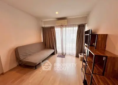 Cozy living room with wooden flooring and natural light from large windows.