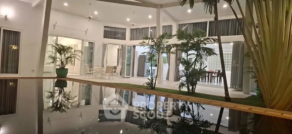 Luxurious modern villa with stunning poolside view and elegant outdoor seating area.