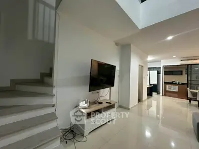 Modern living room with wall-mounted TV and sleek staircase