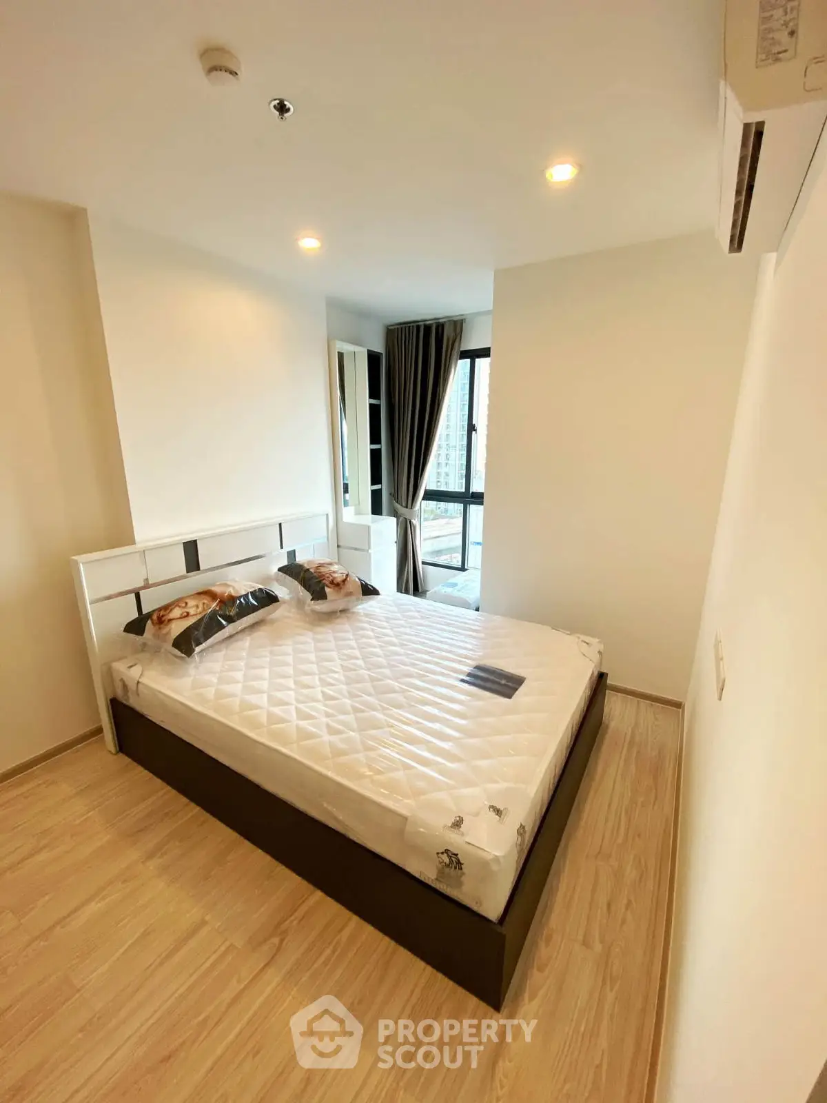Modern bedroom with large window and stylish decor in a high-rise apartment.