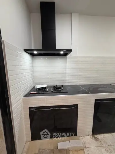 Modern kitchen with sleek black gas stove and stylish white tile backsplash.