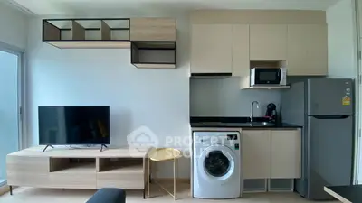 Modern apartment interior with sleek kitchen and living area featuring washing machine and TV.