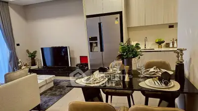 Modern open-plan living room and kitchen with elegant dining setup and sleek appliances.