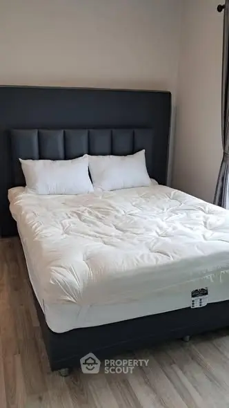 Cozy bedroom with plush bed and elegant headboard, perfect for relaxation.