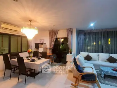 Spacious living and dining area with elegant chandelier and cozy seating.