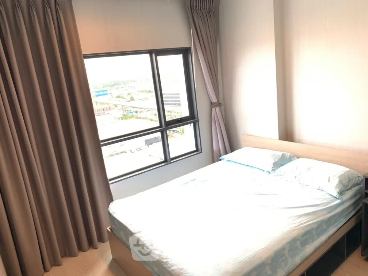 Bright bedroom with large window offering stunning city views and cozy ambiance.