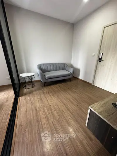 Minimalist living room with sleek gray sofa and wooden flooring