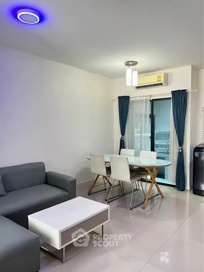 Modern living room with sleek furniture and dining area, featuring stylish lighting and air conditioning.