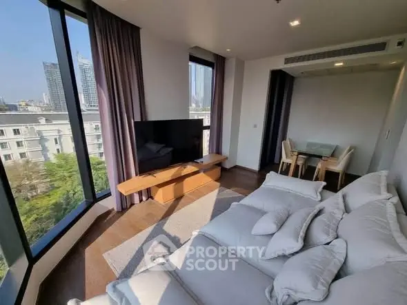 Modern living room with large windows and city view, featuring a cozy sofa and dining area.