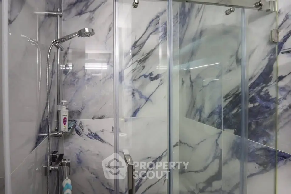 Elegant marble-tiled bathroom with modern glass shower enclosure.