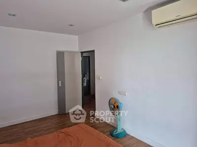 Spacious bedroom with air conditioning and wooden flooring, ideal for comfort and relaxation.