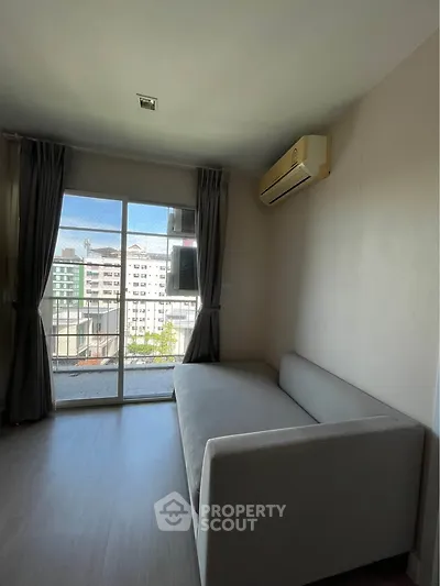 Modern living room with large window and city view, featuring a sleek sofa and air conditioning.
