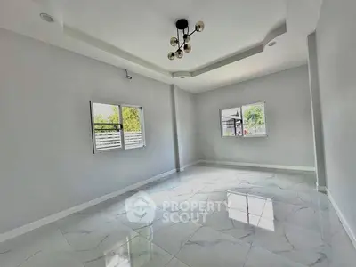 Spacious empty room with modern lighting and large windows, perfect for customization.