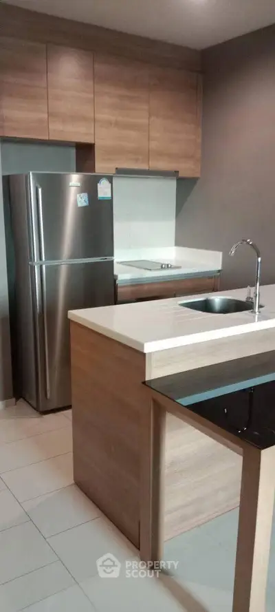 Modern kitchen with sleek cabinetry and stainless steel fridge in a stylish apartment.